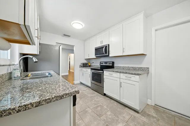 a kitchen with granite countertop a sink stove and refrigerator