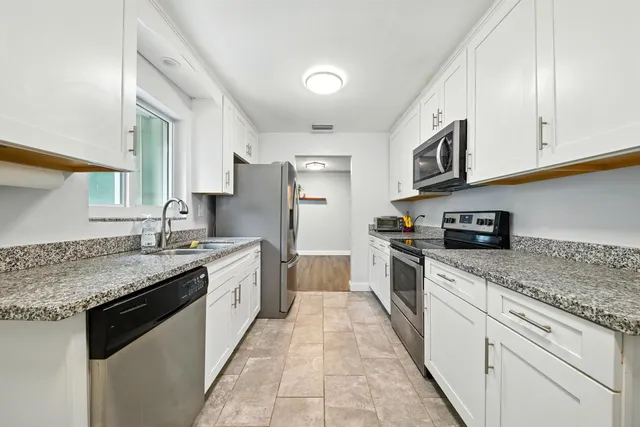 a large kitchen with stainless steel appliances granite countertop a sink stove and cabinets
