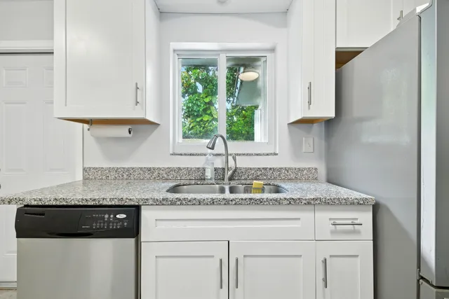 a kitchen with stainless steel appliances granite countertop a sink a stove and a white cabinets