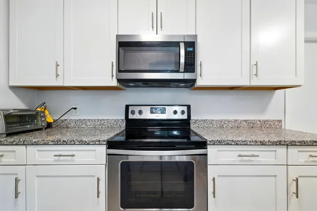 a kitchen with granite countertop white cabinets and a stove a oven with white countertops