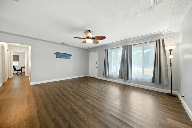a view of an empty room with wooden floor and a window