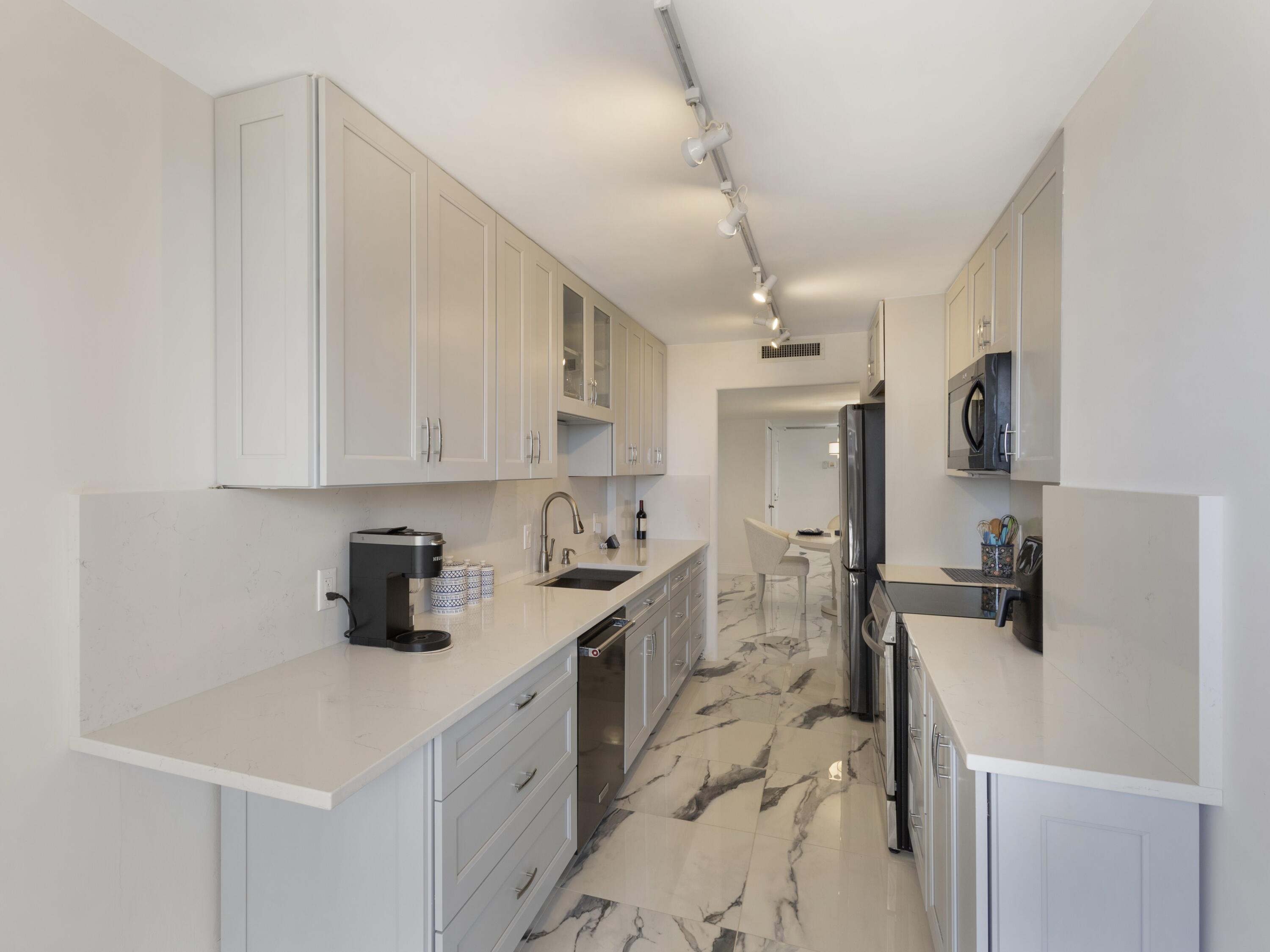 4200 North Ocean Drive, Unit 2301 Singer Island, FL 33404 - Photo 28 of 52 a kitchen with a sink stove and cabinets
