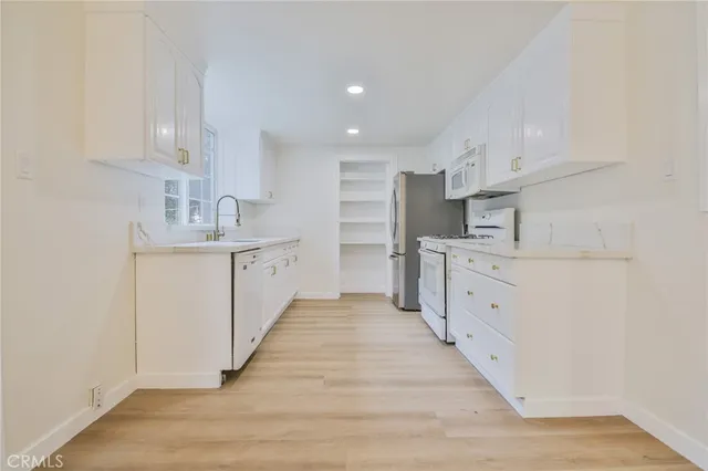 a kitchen with white cabinets appliances and sink