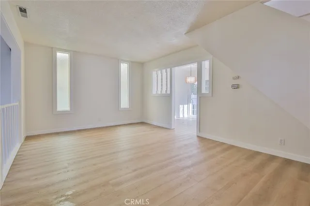a view of an empty room with window and wooden floor