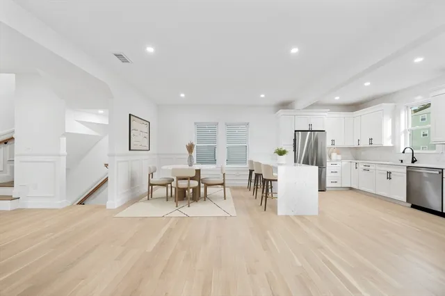 a living room with furniture and kitchen view with wooden floor
