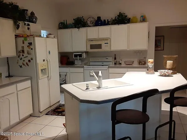 a kitchen with stainless steel appliances a white refrigerator a sink a stove and white cabinets