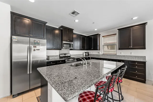 a kitchen with stainless steel appliances granite countertop a refrigerator a sink a stove a microwave and wooden cabinets