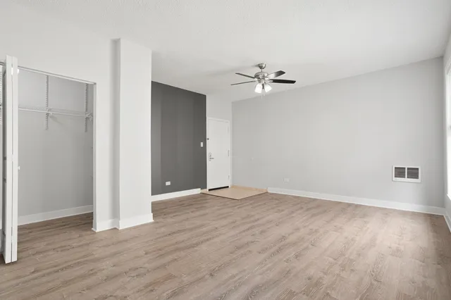 an empty room with wooden floor and ceiling fan