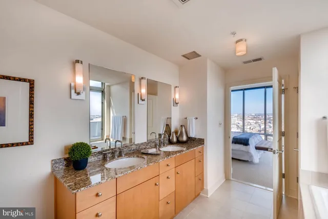 a bathroom with double vanity sinks a large mirror and a shower