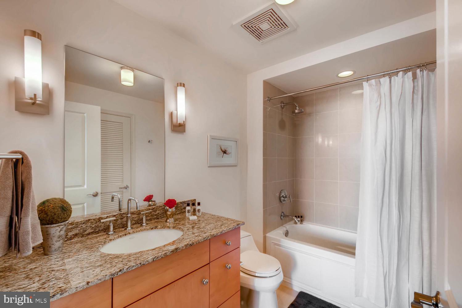 675 President Street, Unit 1806 Baltimore, MD 21202 - Photo 26 of 46 a bathroom with a granite countertop sink toilet a mirror and shower