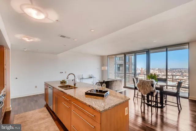 a kitchen with a stove a sink a dining table and chairs with wooden floor