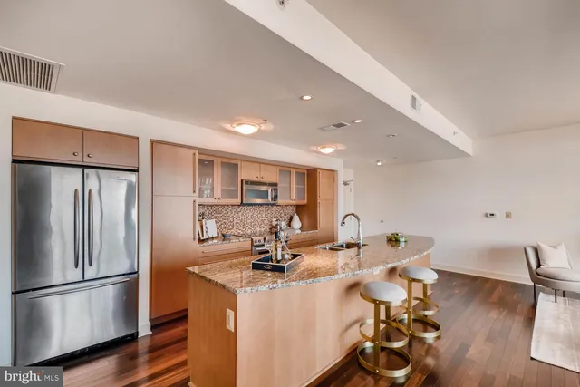 a kitchen with stainless steel appliances a refrigerator a sink a stove and white cabinets with wooden floor