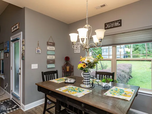 a view of a dining room with furniture a chandelier and large windows