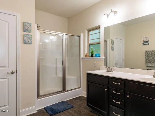 a bathroom with a double vanity sink a mirror and a shower