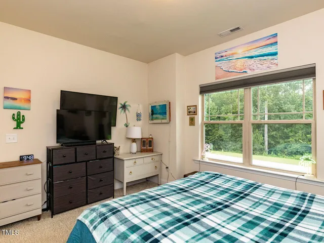 a bedroom with a bed and a flat screen tv on dresser