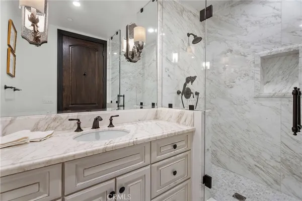 a bathroom with a granite countertop sink a mirror and shower