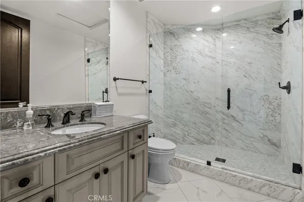 a bathroom with a granite countertop sink a toilet and shower