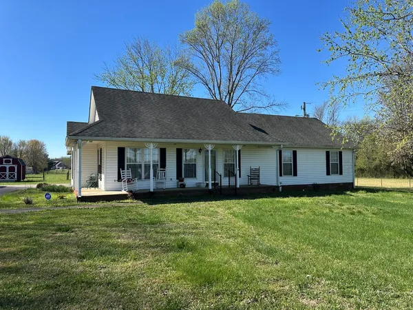 a front view of a house with a garden and trees