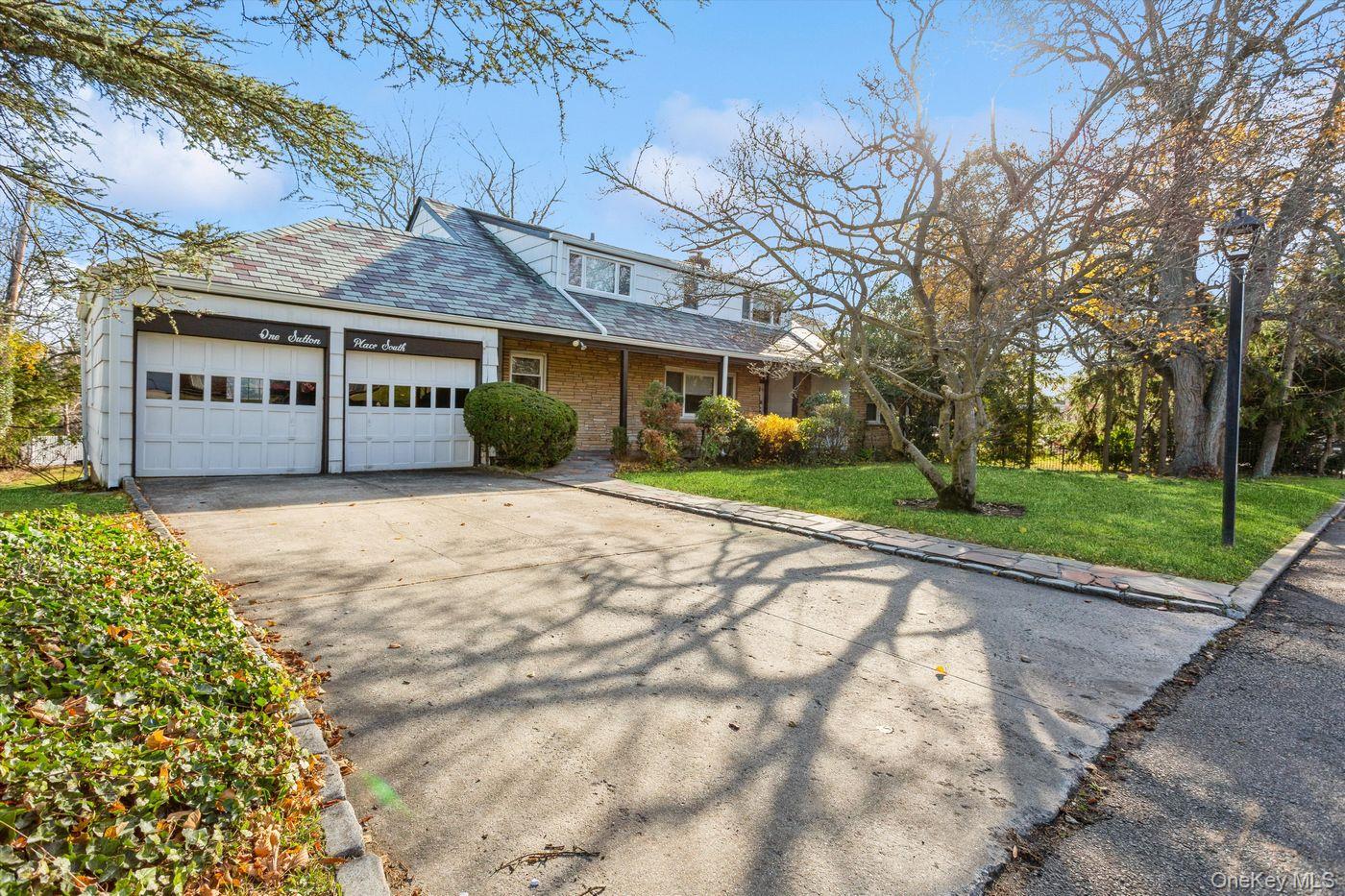 1 Sutton Place Lawrence, NY 11559 - Photo 2 of 38 Traditional-style home featuring a front lawn, driveway, a garage, a porch, and a high end roof