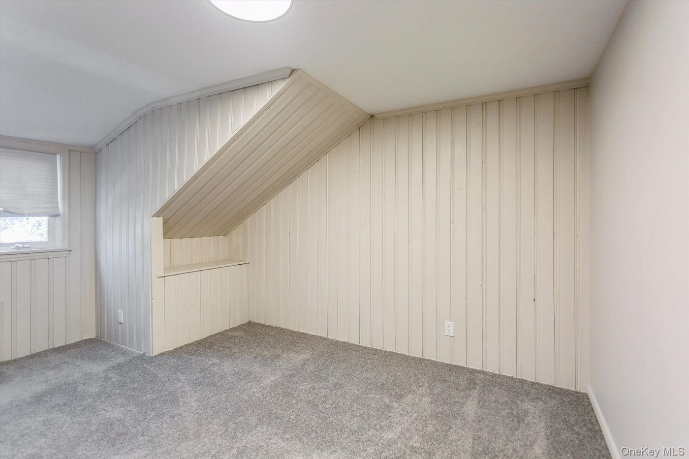 1 Sutton Place Lawrence, NY 11559 - Photo 21 of 38 Additional living space featuring wood walls, carpet flooring, and lofted ceiling