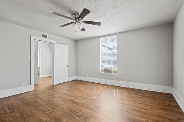 an empty room with wooden floor ceiling fan and windows