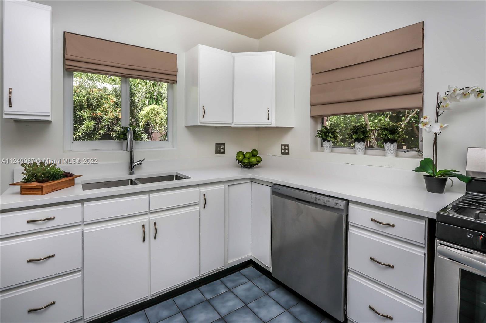 a kitchen with white cabinets a window and appliances