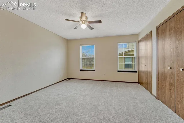 an empty room with closet and a ceiling fan