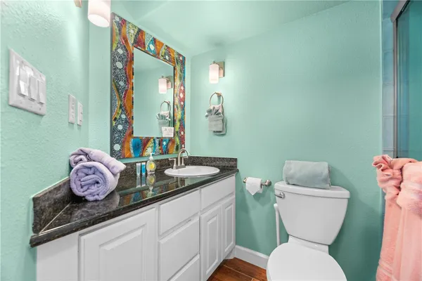 a bathroom with a granite countertop toilet sink and mirror