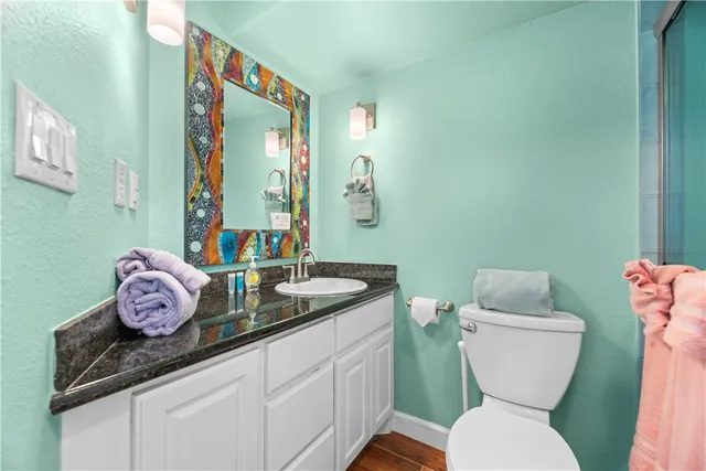 a bathroom with a granite countertop toilet sink and mirror