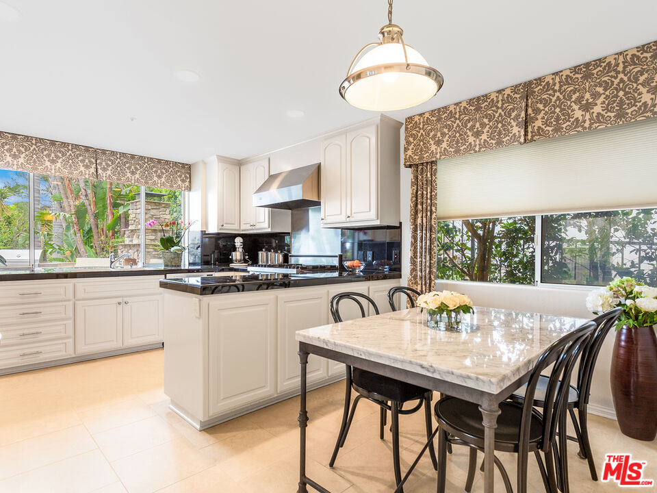 4324 Hillview Drive Malibu, CA 90265 - Photo 12 of 24 a kitchen with stainless steel appliances granite countertop a stove a refrigerator a white table and chairs with wooden floor
