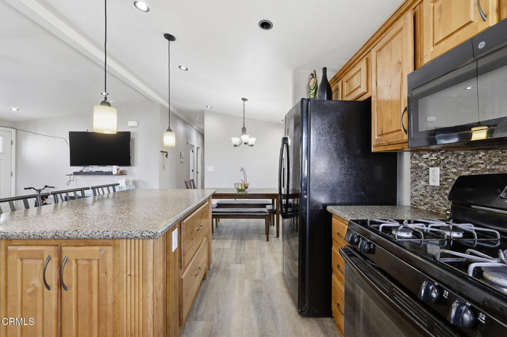1657 Lime Avenue, Unit 87 Oxnard, CA 93033 - Photo 10 of 37 a kitchen with stainless steel appliances granite countertop a stove top oven a sink dishwasher a dining table and chairs with wooden floor
