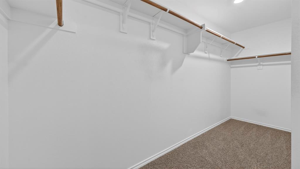 3518 Spring Time Street Forney, TX 75126 - Photo 14 of 31 Spacious closet featuring multiple hanging rods, integrated shelving, white walls, and neutral-toned carpeting
