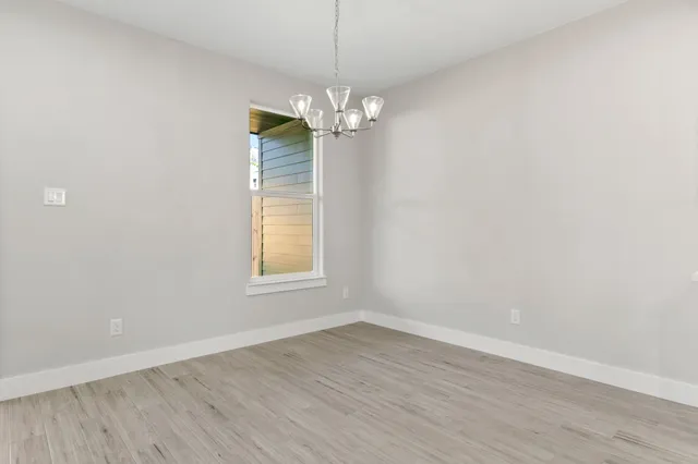 an empty room with ceiling fan and wooden floor