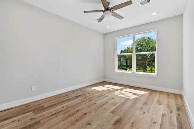 an empty room with ceiling fan and wooden floor