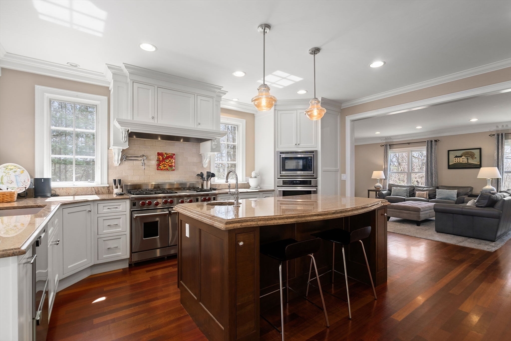 47 Brewster Road Sudbury, MA 01776 - Photo 4 of 41 a kitchen with stainless steel appliances granite countertop a stove a sink dishwasher a refrigerator and a dining table with wooden floor