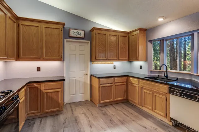 a kitchen with stainless steel appliances granite countertop wooden cabinets a sink and dishwasher a stove with wooden floor