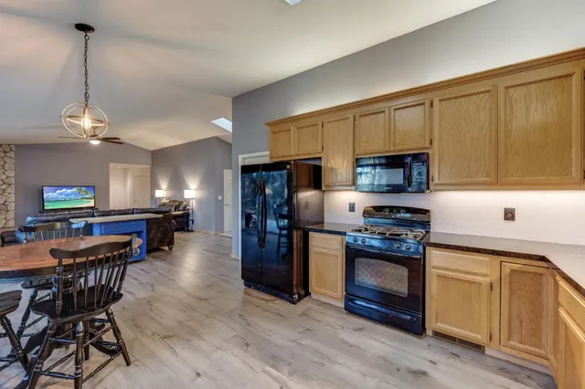 a kitchen with stainless steel appliances a stove a sink a microwave a refrigerator a dining table and chairs