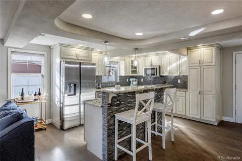 a kitchen with stainless steel appliances a refrigerator a stove a sink and white cabinets with wooden floor