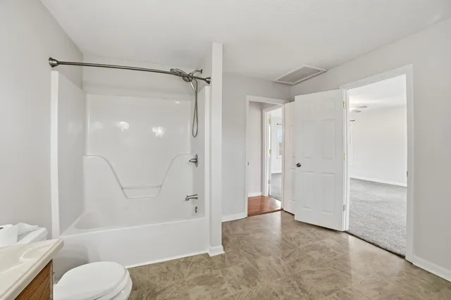 a bathroom with a tub shower sink vanity and a toilet