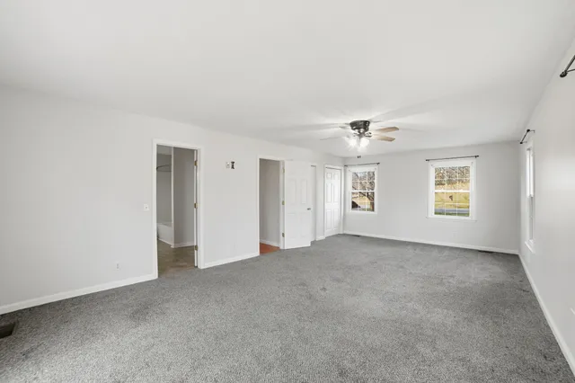 an empty room with windows and ceiling fan