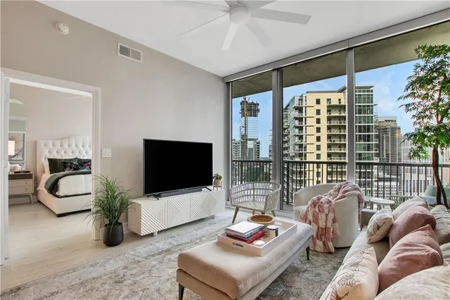 a living room with furniture a flat screen tv and a floor to ceiling window