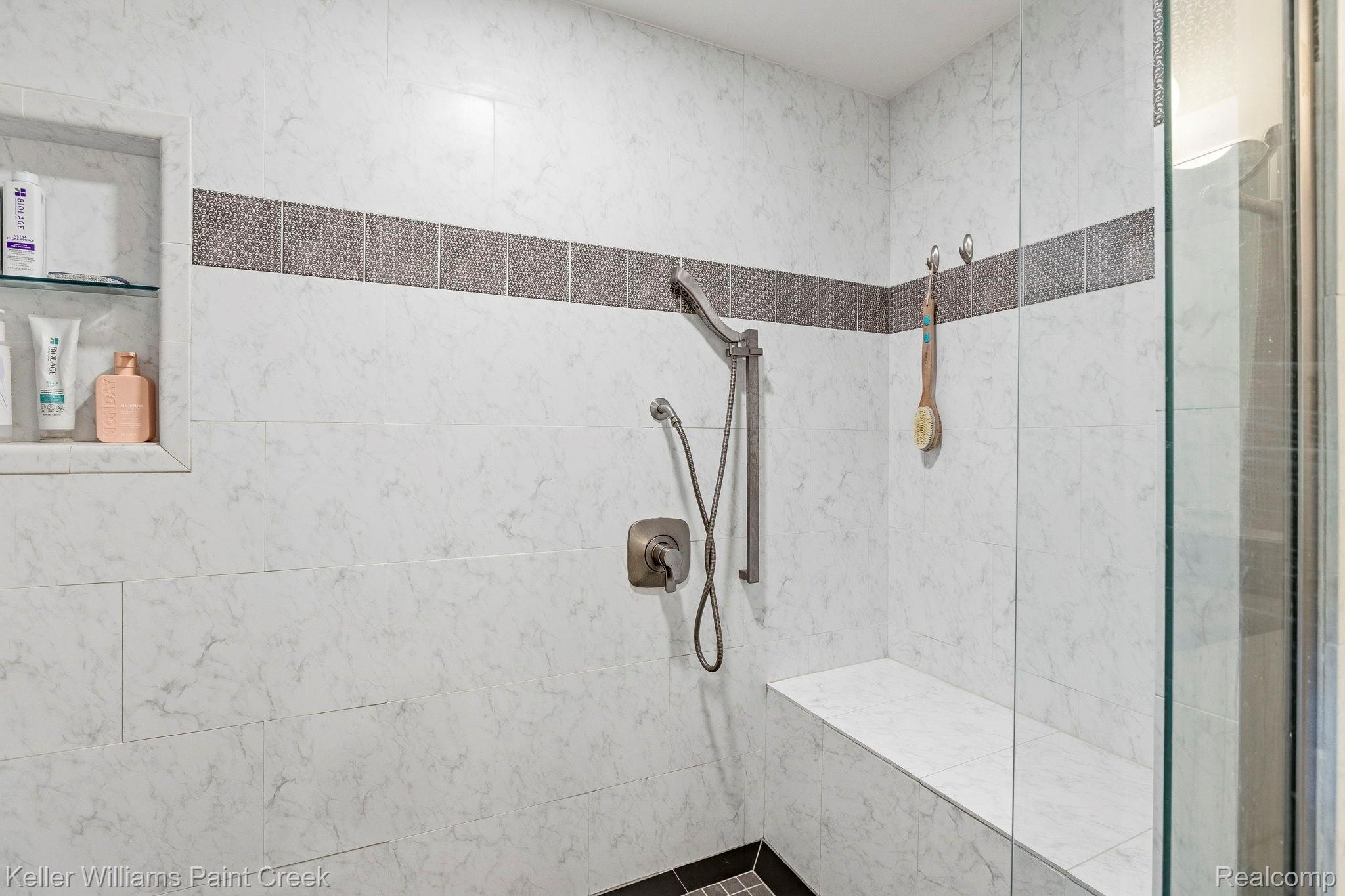1675 North Kilburn Road Rochester, MI 48306 - Photo 37 of 48 Tiled shower enclosure featuring a fixed glass panel, an integrated shower bench, a recessed niche with a glass shelf, and a handheld shower fixture