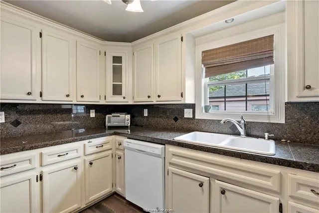 a kitchen with granite countertop white cabinets and a sink