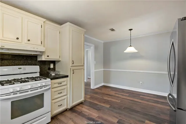 a kitchen with granite countertop a stove cabinets and wooden floor