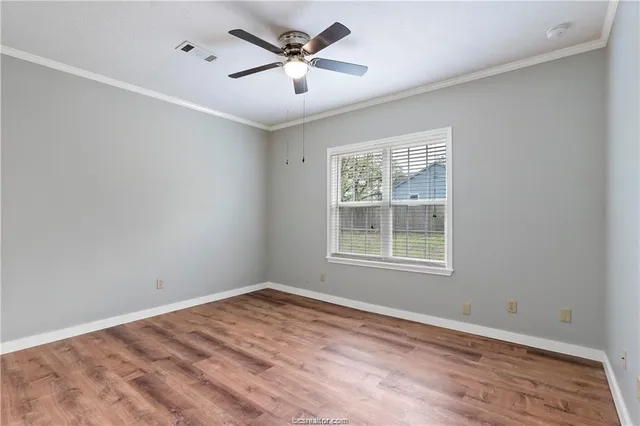 a view of empty room with wooden floor and fan