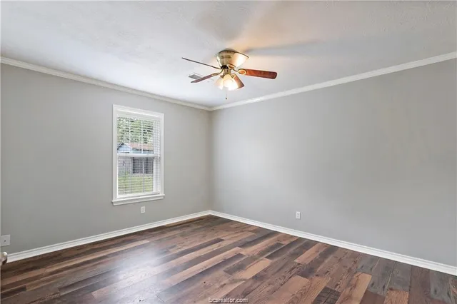 an empty room with wooden floor ceiling fan and windows