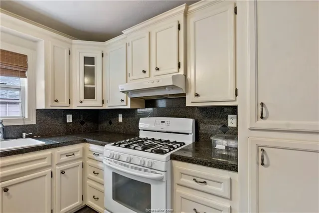 a kitchen with granite countertop white cabinets and white appliances
