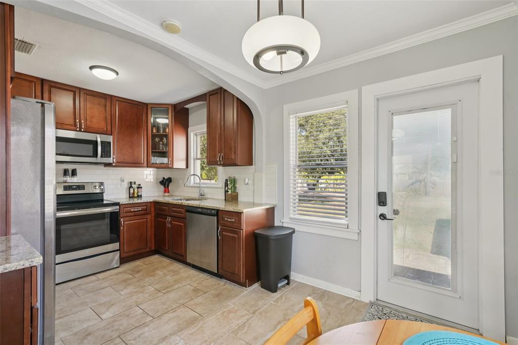 4809 33rd Avenue North St. Petersburg, FL 33713 - Photo 16 of 62 a kitchen with stainless steel appliances granite countertop a stove top oven a sink dishwasher a dining table and chairs with wooden floor