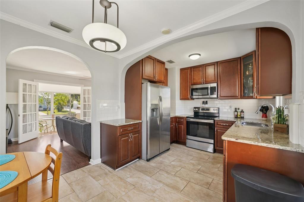 4809 33rd Avenue North St. Petersburg, FL 33713 - Photo 17 of 62 a kitchen with stainless steel appliances granite countertop a refrigerator a stove top oven a sink dishwasher and white cabinets with wooden floor