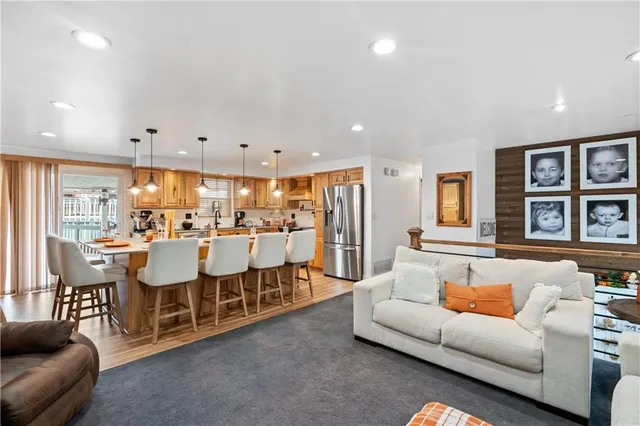 a kitchen with stainless steel appliances granite countertop a stove a sink a refrigerator a dining table and chairs with wooden floor